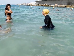 In this image taken from Aug. 29 video, Nesrine Kenza, right, and two unidentified friends wade into the sea in Marseille, southern France. Kenza says she is happy to be free to wear a burkini. (Associated Press)