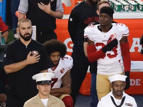 In this Thursday, Sept. 1, 2016 file photo, San Francisco 49ers quarterback Colin Kaepernick, middle, kneels during the national anthem before the team's NFL preseason football game against the San Diego Chargers, in San Diego. NFL Commissioner Roger Goodell disagrees with Kaepernick's choice to kneel during the national anthem, but recognizes the quarterback's right to protest. (AP Photo/Chris Carlson, File)