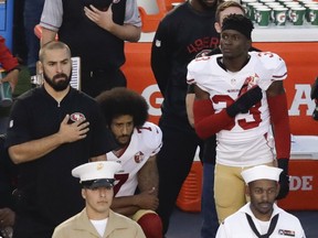 San Francisco 49ers quarterback Colin Kaepernick, middle, kneels during the national anthem before the team's NFL preseason football game against the San Diego Chargers, in San Diego. (AP Photo/Chris Carlson, File)