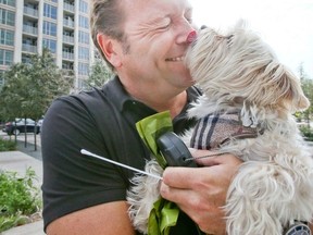 Garry Bradamore, of Poo Prints Canada, holds Winston in front of one of the many condominiums in Toronto on Wednesday. (VERONICA HENRI, Toronto Sun)