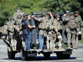 In this Dec. 2, 2015 file photo, an armored vehicle carries police officers near the scene of multiple shootings in San Bernardino, Calif. A lengthy report into the San Bernardino terror attack reveals new details about the killings last year and the way the husband and wife who carried them out died in a police shootout. The report released Friday, Sept. 9, 2016, provides an in-depth look at the chaos and confusion as the Islamic extremists opened fire at a meeting of the man's colleagues. The carnage was described as looking "like a bomb had gone off." (Micah Escamilla/Los Angeles News Group via AP, File)