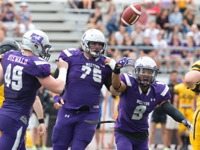 Western Mustangs defensive back Malcolm Brown flips the ball in the air as he and Mustangs players John Biewald (49) and Rupert Butcher (75) celebrate taking possession away from the Waterloo Warriors during their OUA football game at TD Stadium in London, Ont. on Saturday September 10, 2016. The Western Mustangs won the game 75-14.  Craig Glover/The London Free Press/Postmedia Network