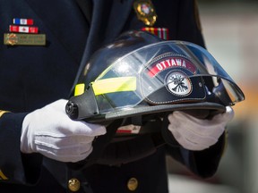 Ottawa Fire Services Deputy Chief, Kim Ayotte, carries a helmet during the 15th Annual Ottawa Firefighters Memorial at the Ottawa Fire Fighters Monument site outside Ottawa City Hall Friday.