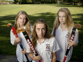 The city says it will allow high school sports teams to use Minto Field without paying an extra fee. Claire Adams, Jayden Alp, and Tay Barnabe, members of the championship-defending Nepean High School varsity field hockey team, pose for a photo at their school's field where they would have had to practise this season if the city charged rental fees at Minto Field. (Errol McGihon/Postmedia)