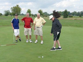 Lonnie Sarazin, right, watches his putt slide by the hole as his great-grandson Andrew, far left, his grandson Jason, red shirt, and his son Jim look on the first green at The Landings. (Supplied photo)