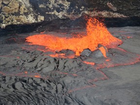 In this Sept. 10, 2016, photo released by the U.S. Geological Survey shows the east edge of Halemaumau Crater spattering lava at the south corner of the Kilauea's summit lake after it rose over the weekend, to within about 5 m (16 ft) of the floor of Halemaumau Crater, before dropping back down slightly with the onset of spattering in the Hawaii Volcanoes National Park, in Hawaii. (Tim Orr/U.S. Geological Survey via AP)