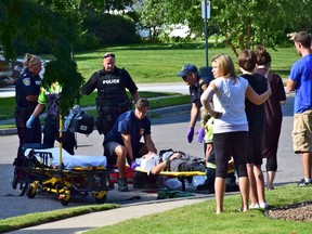 Paramedics assist an injured pedestrian following a violent assault in the city's south end Monday. Sarnia police are now searching for the driver of a white Mazda hatchback wanted in connection to the assault that occurred in the area of Lincoln Park Avenue and Cecil Street. (Photo courtesy of NORA PENHALE)