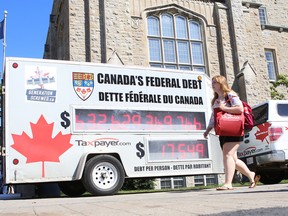 A student walks past the Canadian Taxpayers Federation's federal debt clock at Queen's University in this file photo. (Elliot Ferguson/The Whig-Standard)