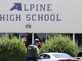 A United States Border Patrol officer patrols the perimeter at Alpine High School after a shooting Thursday, Sept. 8, 2016, in Alpine, Texas. 14-year-old girl died of an apparent self-inflicted gunshot wound after shooting and injuring another female student Thursday inside th school, according to the local sheriff. (Jacob Ford/Odessa American via AP)