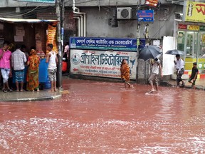 In this Tuesday, Sept. 13, 2016 photo, people wade past a road turned red after blood from sacrificial animals on Eid al-Adha mixed with water from heavy rainfall in Dhaka, Bangladesh. Authorities in Dhaka had assigned several places in the city where residents could slaughter animals, but the heavy downpours Tuesday meant few people could use the designated areas. (AP Photo)