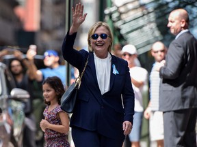 U.S. Democratic presidential nominee Hillary Clinton waves to the press as she leaves her daughter's apartment building after resting on September 11, 2016, in New York. Clinton greeted the young girl behind her with a hug. (Brendan SmialowskiBRENDAN SMIALOWSKI/AFP/Getty Images)