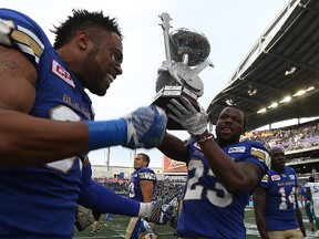 Winnipeg Blue Bombers DB Kevin Fogg (right) and DE Justin Cole celebrates with the Banjo Bowl after a defeat of the Saskatchewan Roughriders during CFL action in Winnipeg on Sat., Sept. 10, 2016. The Bombers cut Cole on Tuesday, May 9, 2017.