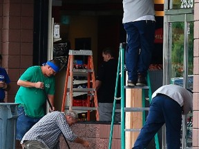 Construction workers continue cleaning up in front of a QuickTrip store hours after a driver plowed into two police officers Tuesday, Sept. 13, 2016, in Phoenix. Police said Marc LaQuon Payne, 44, apparently drove his vehicle at the officers before hitting a patrol car and crashing into the front of the store around 2 a.m. Tuesday. (AP Photo/Ross D. Franklin)