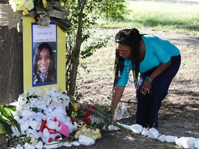 In this July 21, 2015 photo, Jeanette Williams places a bouquet of roses at a memorial for Sandra Bland near Prairie View A&M University, in Prairie View, Texas. The family of Bland, a black Chicago-area woman who died in a Texas jail after a contentious traffic stop last summer, has reached a settlement in their wrongful death lawsuit, the family's attorney told a Houston television Thursday, Sept. 15, 2016. (AP Photo/Pat Sullivan, File)
