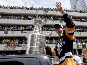 Pittsburgh Penguins’ Sidney Crosby waves to the crowd while holding onto the Stanley Cup while riding along the victory parade route in Pittsburgh, Pa., Wednesday, June 15, 2016. (THE CANADIAN PRESS/AP Photo/Keith Srakocic)
