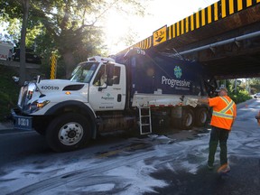 City of London employees work to contain hydraulic oil spilled when a Progressive Waste Solutions garbage truck became lodged underneath a railway bridge on Talbot Street about 8 a.m. in London, Ont. on Thursday September 15, 2016. The bridge has been a long-standing trouble spot for trucks in the city, even with signs marking the 3.3 metre height on large I-beams that were installed fore and aft to prevent the large vehicles from striking the rail bridge itself. (CRAIG GLOVER, The London Free Press)
