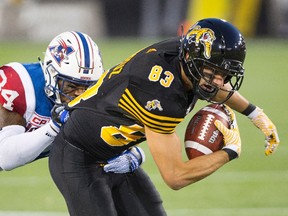 Alouettes linebacker Kyries Hebert (34) gets ahold of the jersey of Tiger-Cats wide receiver Andy Fantuz (83) during first half CFL action in Hamilton on Friday, Sept. 16, 2016. (Peter Power/The Canadian Press)