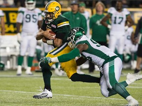 The Edmonton Eskimos' quarterback Mike Reilly (13) is tackled by the Saskatchewan Roughriders' Ese Mrabure (98) during second half CFL action at Commonwealth Stadium, in Edmonton on Friday Aug. 26, 2016.