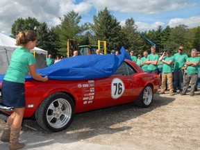 A cover is lifted from a restored Chevy Camaro during an open house Thursday in honour of the 40th anniversary of Steelway Building Systems. The vehicle is in tribute to the members of the Steelway family who have died over the 40 years. The number 76 is a reference to 1976, the year the company was founded.