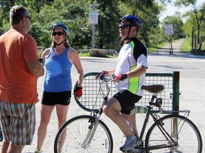 Cyclists Andrea Wist and Chris Hogan speak with Doug Mathany, a Bluewater Trails Committee volunteer, at an open house Sunday about improvements to the Howard Watson Nature Trail. One is a gateway project at the Michigan Avenue entrance, pictured in the background. (Tyler Kula/Sarnia Observer/Postmedia Network)