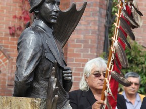 Chapleau Cree Chief Keith Corston proudly holds the Eagle Staff beside the newly unveilled Charles Byce Statue.