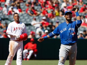 Blue Jays first baseman Edwin Encarnacion waves his glove at a swarm of bees in the third inning of a game against the Angels in Anaheim, Calif., on Sunday, Sept. 18, 2016. (Christine Cotter/AP Photo)