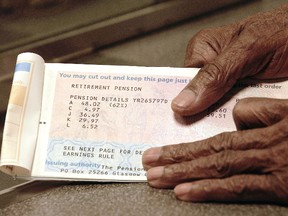 An elderly man handles in his pension book at the post office February 27, 2003 in London. (Photo by Graeme Robertson/Getty Images)