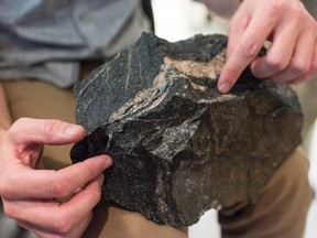 University of Alberta scientist Jesse Reimink points to the dark bands in the which make up the oldest part of the rock in this handout image. The lighter bands are younger portions of rock that intruded into the 4.02 billion-year-old rock at a later time. THE CANADIAN PRESS/HO-University of Alberta-John Ulan