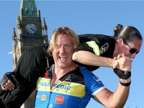 Paramedic Martin Johnson got a little excited upon reaching Parliament Hill, hoisting fellow paramedic Sara Salvis over his head instead of his bike. JULIE OLIVER / POSTMEDIA