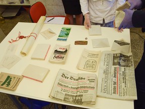 In this photo taken Sept. 13, 2016 at the National Museum's laboratory in Szczecin, Poland, the content is shown of a Nazi-era time capsule. The copper capsule was found Sept. 6, 2016 in the northwestern town of Zlocieniec, Poland, in the remains of the foundations of a Nazi training center that was built there in 1934, when the town was in Germany and was called Falkenburg. When opened on Sept. 13, the container revealed newspapers, photographs, the center's founding act on parchment and two copies of Hitler's 'Mein Kampf' which are lying with their back covers up, to conceal the title, as spreading Nazi ideas is not allowed in Poland. (AP Photo/Sebastian Kuropatnicki)