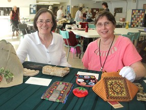 Theresa Lawrence, left, and Donna Hamilton, from the Cataraqui Guild of Needle Arts, at a meeting of the members in Kingston on Monday show a portion of the historic display of bags and purses that will be part of their guild's annual show in October. (Michael Lea,/The Whig-Standard)