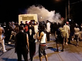 Police fire tear gas into the crowd of protesters on Old Concord Road late Tuesday night, Sept. 20, 2016, in Charlotte, N.C. A black police officer shot an armed black man at an apartment complex Tuesday, authorities said, prompting angry street protests late into the night. The Charlotte-Mecklenburg Police Department tweeted that demonstrators were destroying marked police vehicles and that approximately 12 officers had been injured, including one who was hit in the face with a rock. (Ely Portillo/The Charlotte Observer via AP)