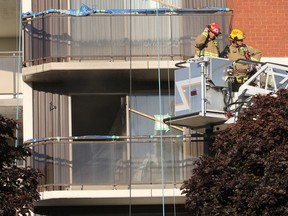 Firefighters stand in the bucket of a ladder truck outside a third-floor apartment that caught fire Wednesday morning on Leroy Grant Drive in Kingston, Ont. on Wednesday, Sept. 21, 2016. Michael Lea The Whig-Standard
