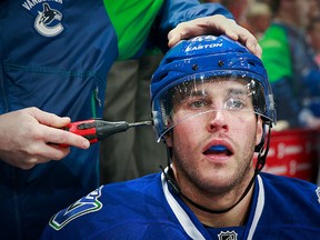 Matt Bartkowski of the Vancouver Canucks gets his helmet adjusted during their NHL game against the Chicago Blackhawks at Rogers Arena March 27, 2016 in Vancouver. (Jeff Vinnick/NHLI via Getty Images)