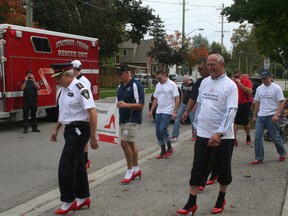 A group of men, including then Strathroy-Caradoc Police Chief Rick Beazly (left) and Lambton-Kent-Middlesex MP Bev Shipley (right), participate in the Walk a Mile in Her Shoes event in Strathroy in 2011. File photo.