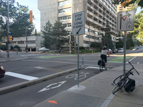 A cyclist stops at Laurier Avenue and Bay Street where the stop lines for vehicles have been moved back and for cyclists ahead, increasing the distance between the two to five metres (Susana Mas, Postmedia)