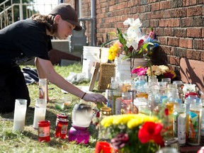 Seth Conlin, 16, lights candles at a roadside memorial for Steven Medeiros, an avid motorcyclist killed in a Hamilton Road crash this week. (CRAIG GLOVER, The London Free Press)