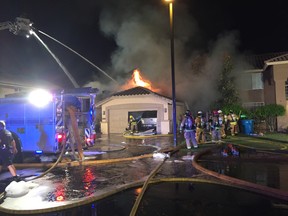 Firefighters extinguish flames caused by a plane crashing into a home in Gilbert, Ariz., on Saturday, Sept. 17, 2016. Federal investigators are trying to determine what led the plane carrying several skydivers to crash. The pilot and four skydivers were able to parachute out. (Gary Hildebrandt/Gilbert Fire Department via The AP)