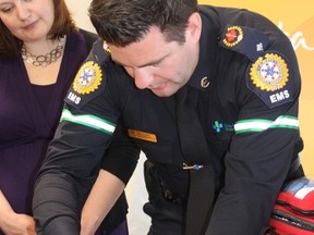 Alex Campbell, public education officer for Emergency Medical Services in the Edmonton area, demonstrates how the Electronic Point of Care machine can test blood for electrolytes and blood gasses with a single drop of blood - Photo by Crystal St. Pierre.
