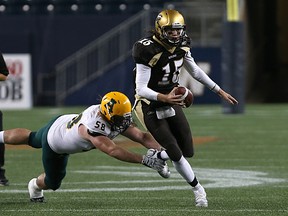 University of Manitoba Bisons QB Theo Deezar (right) avoids a tackle attempt from University of Alberta Golden Bears DL Garrett Meek during Canada West football action in Winnipeg on Fri., Sept. 16, 2016.