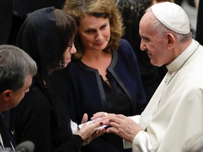 Pope Francis blesses a photo he is shown on a smartphone during a meeting with relatives of Nice's attack victims during a special audience in the Pape Paul IV hall, at the Vatican, Saturday, Sept. 24, 2016. (AP Photo/Andrew Medichini)