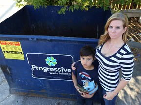 Kristine Kennedy and her son Finnley, 7, pose near a dumpster in the Corydon village area of Winnipeg on Wed., Sept. 14, 2016. Kennedy said was forced to retrieve some toys and other personal items from the dumpster when the person buying her condo entered before the possession date and discarded them.