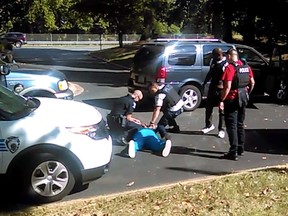 In this image taken from video recorded by Keith Lamont Scott's wife, Rakeyia Scott, on Tuesday, Sept. 20, 2016, Charlotte police squat next to Keith Lamont Scott as Scott lies face-down on the ground, in Charlotte, N.C. In the video of the deadly encounter between Charlotte police and the black man, Rakeyia Scott repeatedly tells officers her husband is not armed and pleads with them not to shoot him as they shout at him to drop a gun. The video does not show clearly whether Scott had a gun. (Rakeyia Scott/Curry Law Firm via AP)