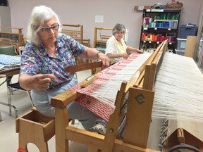 Patricia Silver, left, and Nancey Orosz of the London District Weavers and Spinners use a 254-cm jack loom to create a red and white bed cover.                        (DEREK RUTTAN, The London Free Press)