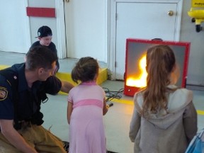 A child learns how to put out a fire using an electronic fire extinguisher during the 2014 open house. File photo.