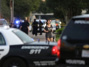 Jennifer Molleda runs down Wesleyan Street in Houston to find her husband, Alan Wakim, who had two bullets whiz by his face after going through his windshield on the way to work along Wesleyan at Law Street in a shooting that left multiple people injured and the alleged shooter dead, Monday morning, Sept. 26, 2016. (Mark Mulligan/Houston Chronicle via AP)