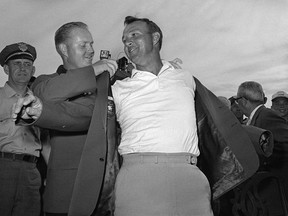 In this April 12, 1964 file photo, Arnold Palmer, right, slips into his green jacket with help from Jack Nicklaus after winning the Masters golf championship, in Augusta, Ga. (AP Photo)
