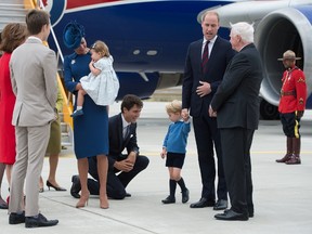 Prime Minister Justin Trudeau (C) kneels to talk to Prince George as his father Prince William, The Duke of Cambridge, speaks with the Governor General David Johnston (R) and Catherine, The Duchess of Cambridge (C) holds their daughter Princess Charlotte upon arrival at 443 Maritime Helicopter Squadron base on September 24, 2016, in Victoria, British Columbia. (The Canadian Press/JONATHAN HAYWARD)