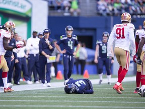 Seattle Seahawks quarterback Russell Wilson stays down after injuring his knee after being tackled by San Francisco 49ers outside linebacker Eli Harold in the second half of an NFL football game on Sept. 25, 2016. (AP Photo/Ted S. Warren)