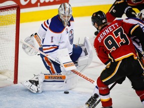 Edmonton Oilers goalie Laurent Brossoit, left, stops a shot from Calgary Flames' Sam Bennett during third period pre-season NHL split-squad hockey action in Calgary, Monday, Sept. 26, 2016.